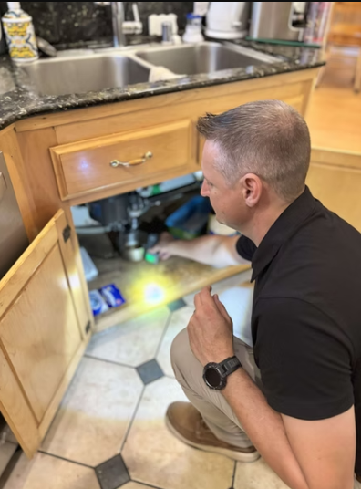 PurePoint inspector checking plumbing beneath a kitchen sink during a home inspection